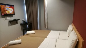 A hotel room with a double bed, a TV on the wall, a small table with a lamp, and a window with curtains. - Grandpa Hotel (Port Dickson)