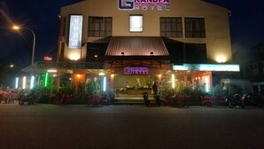 A hotel with a neon sign, outdoor seating, and a visible entrance. - Grandpa Hotel (Port Dickson)