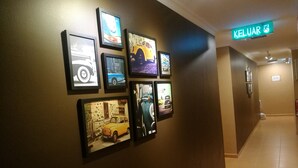 A hallway with framed pictures of cars on the wall and a 'KELUAR' sign above. - Grandpa Hotel (Port Dickson)