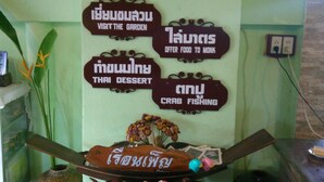 A room with a green wall, a clock, and several signs with Thai text.