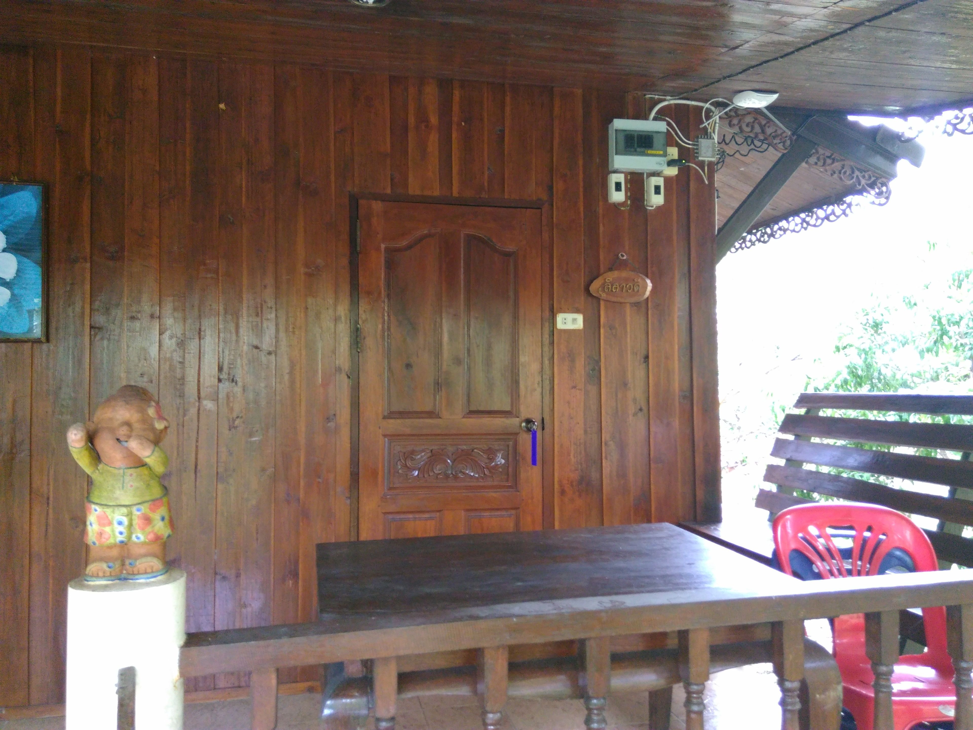 A wooden interior with a door, a bench, and a red chair.