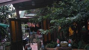 A brick entrance with a metal gate, a motorcycle parked inside, and a dog lying on the ground.