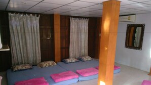 A room with a large bed, wooden pillars, and a mirror on the wall.