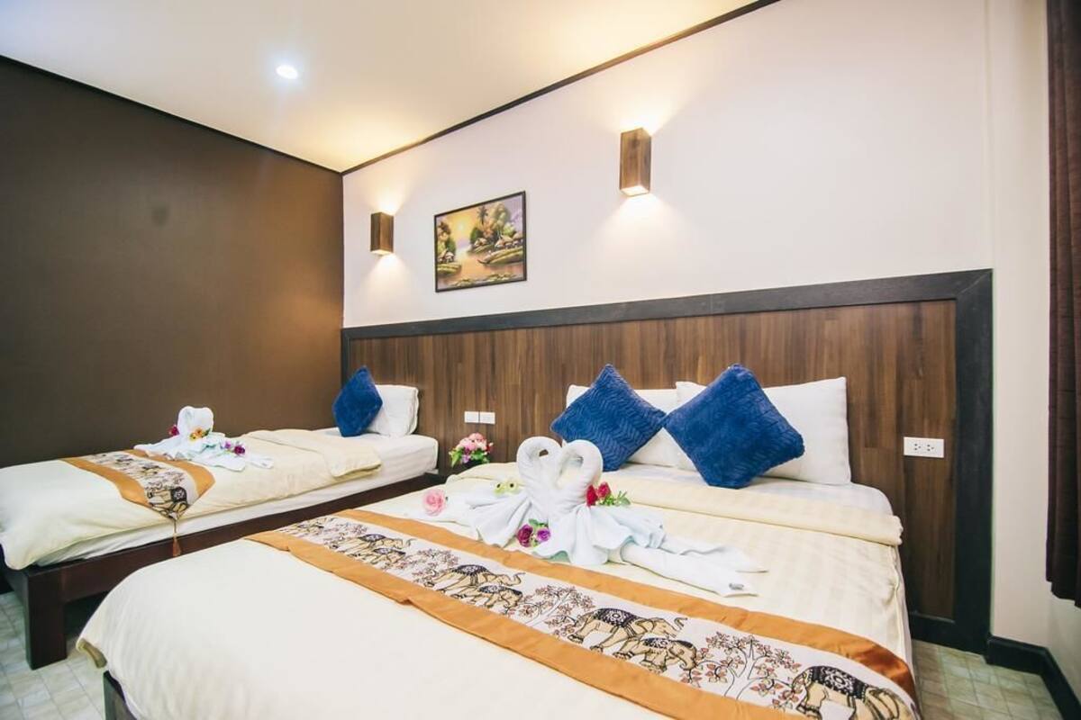 A hotel room with two beds, each with a neatly made bed, pillows, and a decorative towel arrangement.