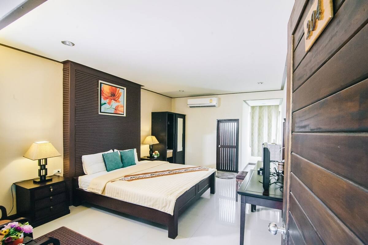 A hotel room with a bed, bedside tables, a desk, and a chair.