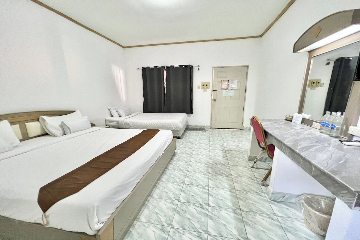 Habitación de hotel con dos camas, baño y una mesita de noche con artículos de aseo.