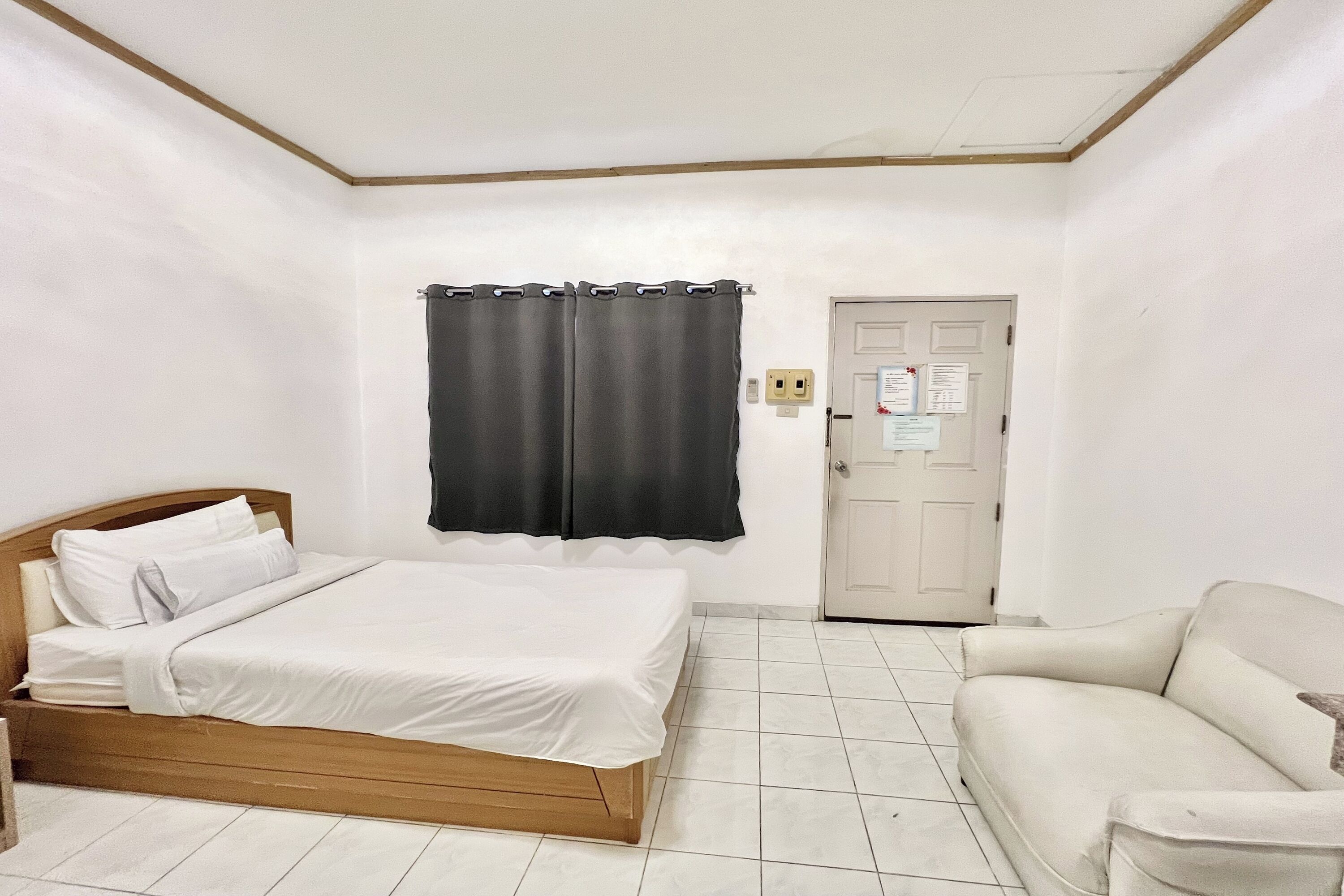 Une pièce comprenant un lit, un canapé, une porte et un interrupteur fixé au mur.