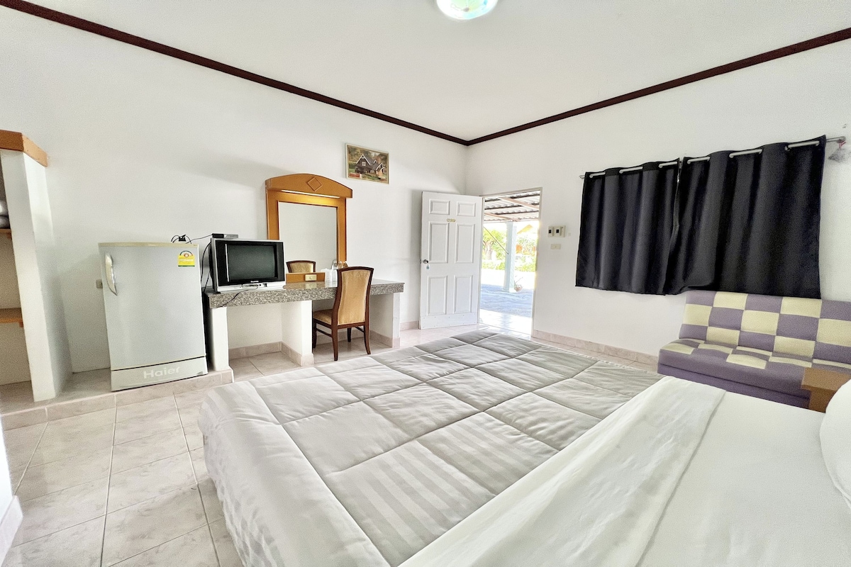 Una habitación de hotel con una cama, un escritorio con una silla, una televisión y una puerta que da al exterior.