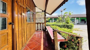 Une façade en bois avec une enseigne portant le nom «Isabela», une véranda carrelée et, au fond, un bâtiment vert.