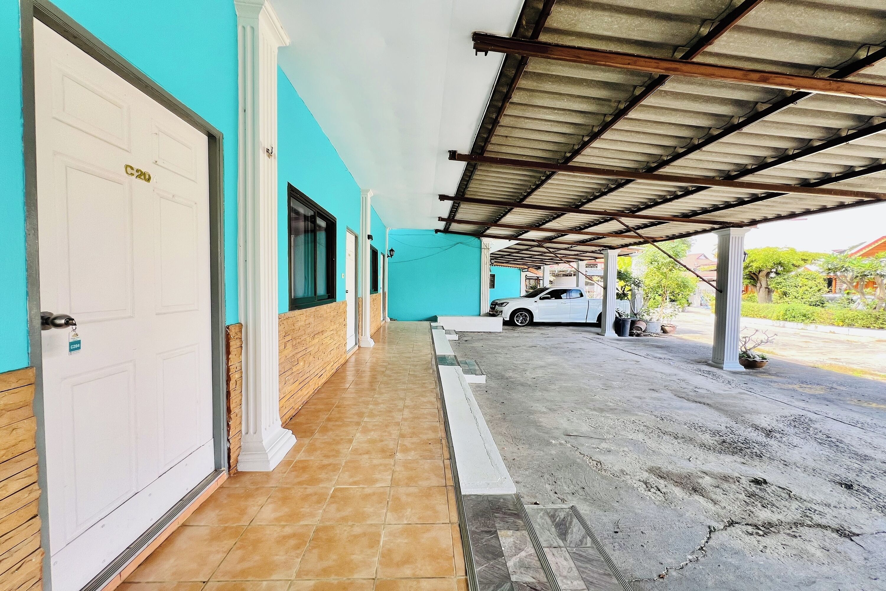 A covered parking area with a white door labeled "C20" and a white car parked inside.