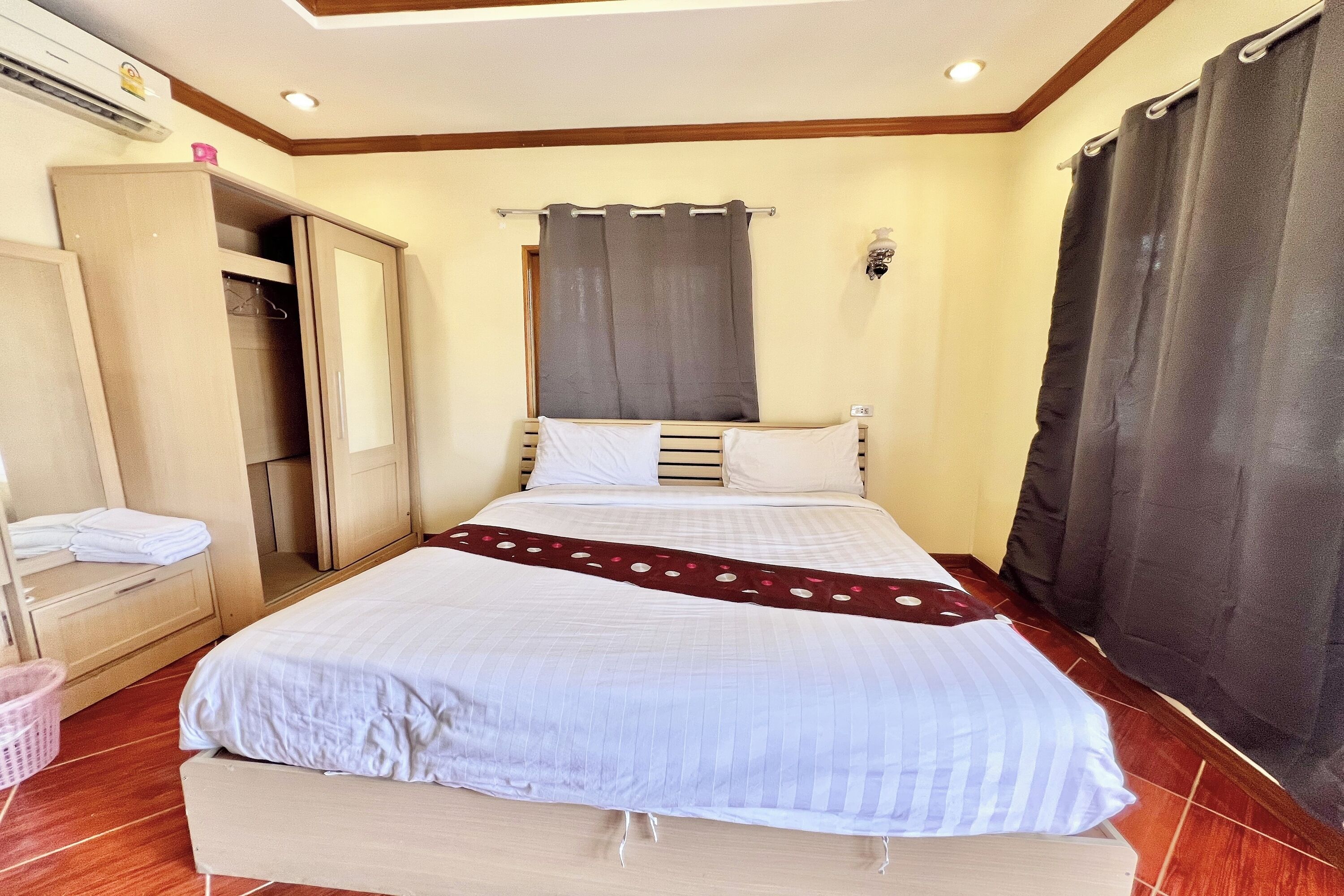 A neatly arranged bedroom with a bed, a wardrobe, and a mirror.