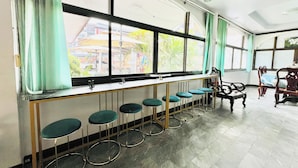 Un espace bar doté d’un long comptoir, de tabourets de bar et offrant une vue sur l’extérieur grâce à de grandes fenêtres.