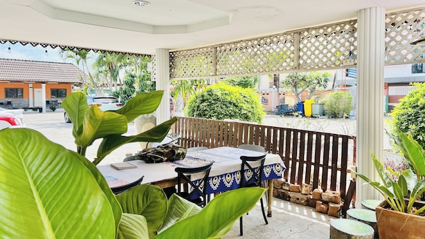 Un espace extérieur aménagé en terrasse, avec une table et des chaises, entouré de verdure et délimité par une clôture en bois.