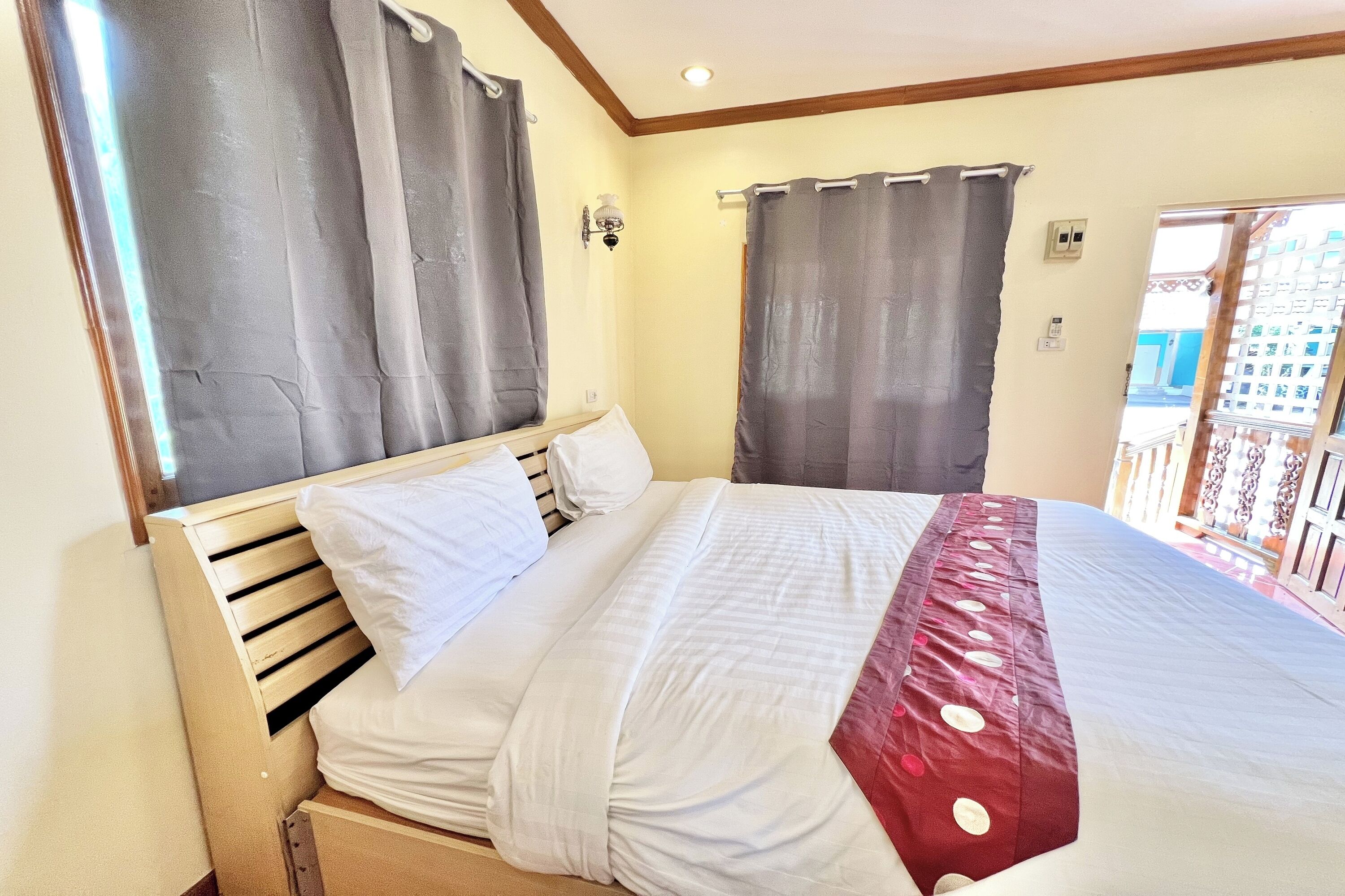 A hotel room with a bed, curtains, a light fixture, and a view of the outside.