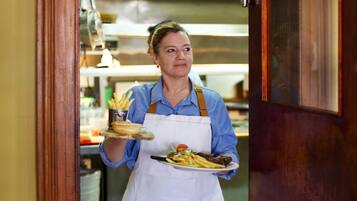 A person in a kitchen holding a tray with food items.