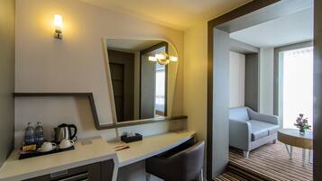 A hotel room with a desk, chair, and a sofa.