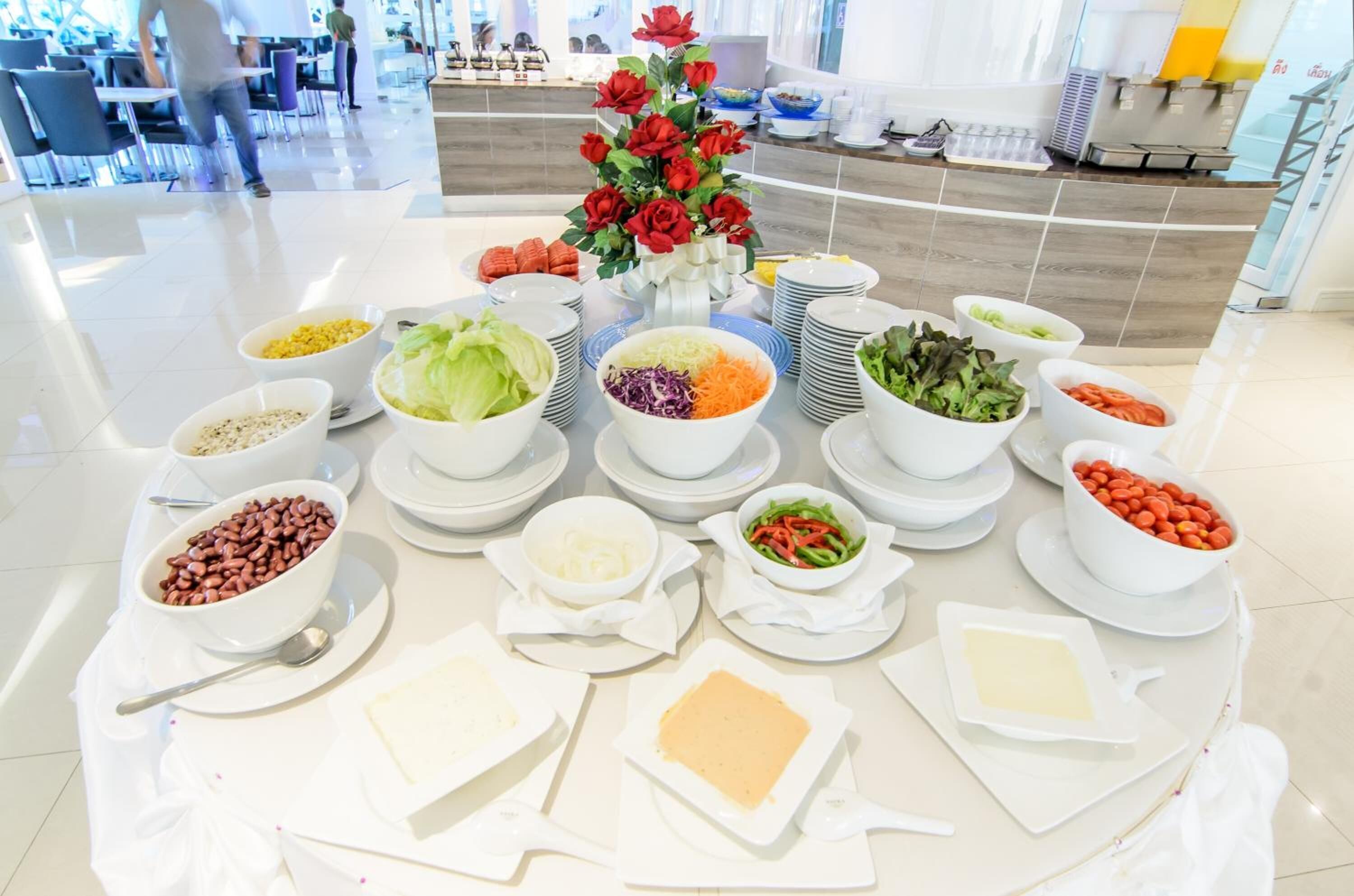Una mesa de buffet con diferentes platillos y un centro de rosas rojas.