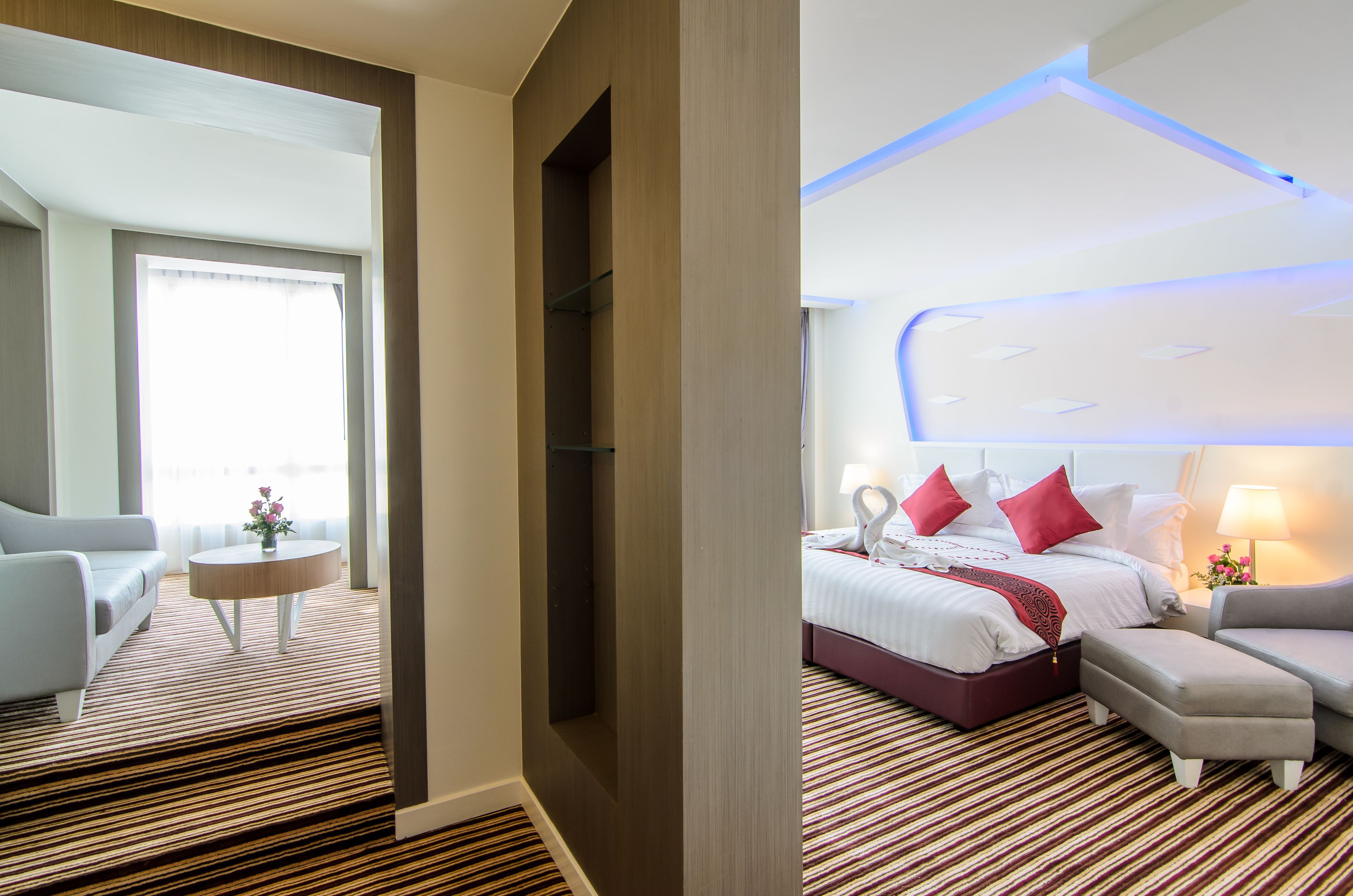 A hotel room with a bed, a sofa, a small table, and a window.