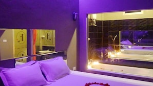 A hotel room with a bed, a large window, and a heart-shaped decoration made of rose petals on the bed. - Heaven Inn (Si Racha)