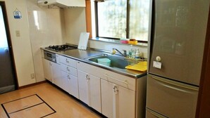 Una cocina compacta con estufa a gas, lavamanos y refrigerador.