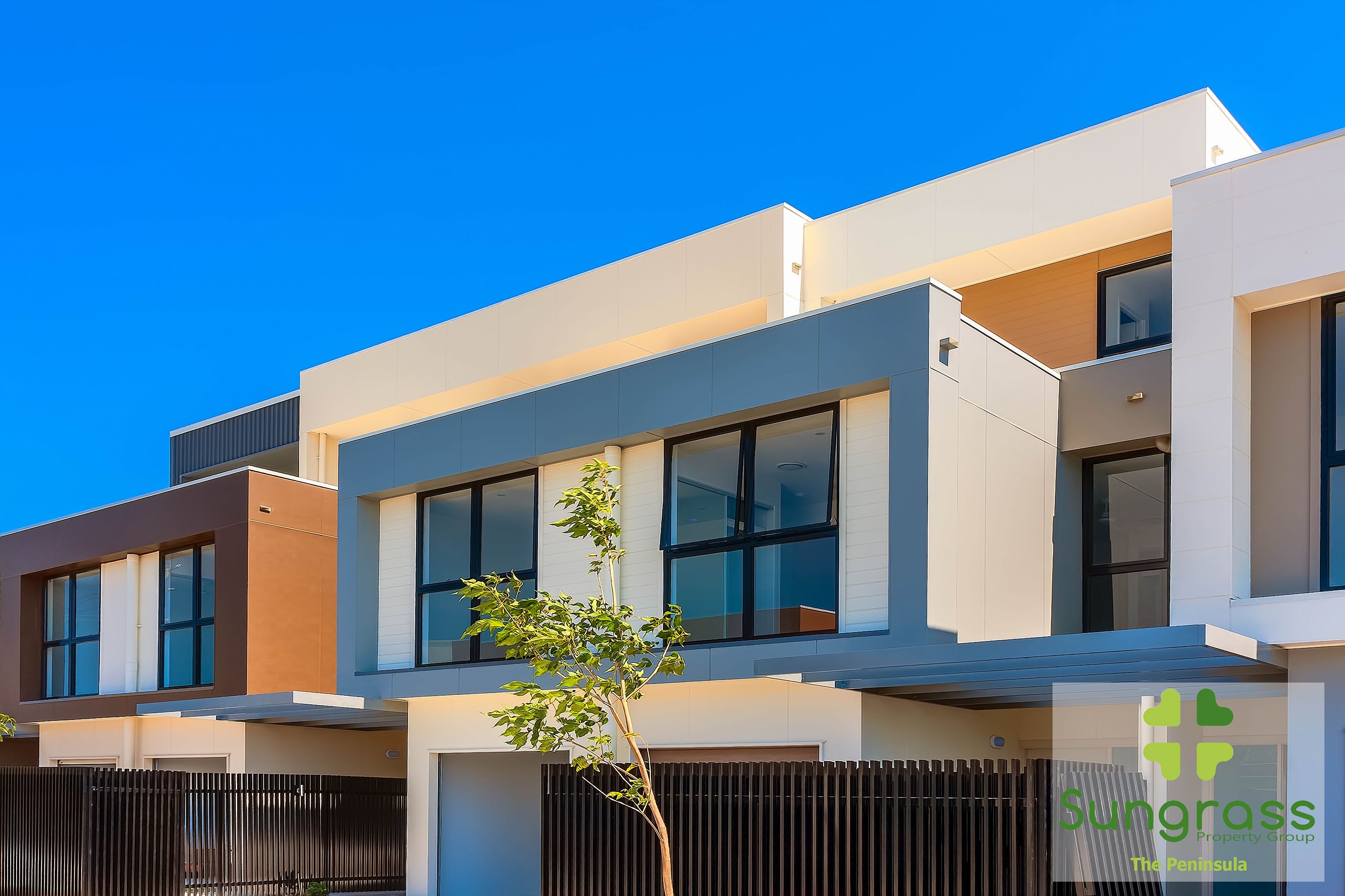 A modern multi-story residential building with large windows and a flat roof.
