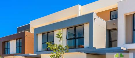 A modern multi-story residential building with large windows and a flat roof.