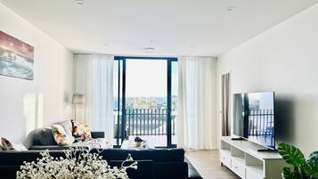 Una sala de estar moderna con un sofá, un televisor y un balcón con cortinas.