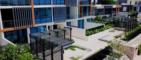 Un edificio moderno con varios balcones, un jardín en la azotea y una arquitectura que combina vidrio y concreto.