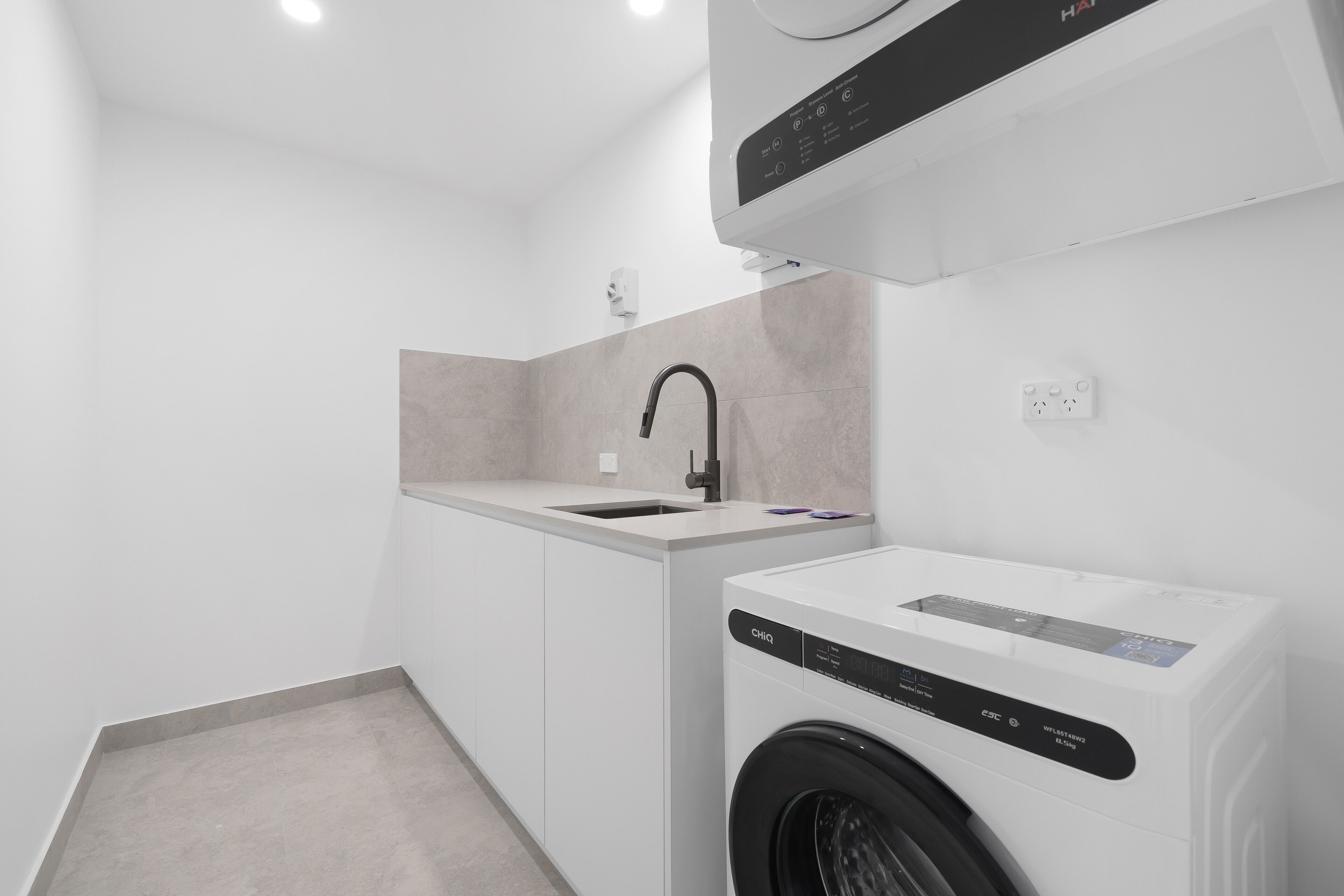 Cocina compacta con lavadora integrada, un lavamanos y una encimera.