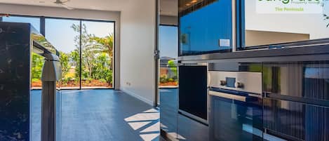 A modern kitchen with a Bosch oven, a large window, and a view of greenery outside.