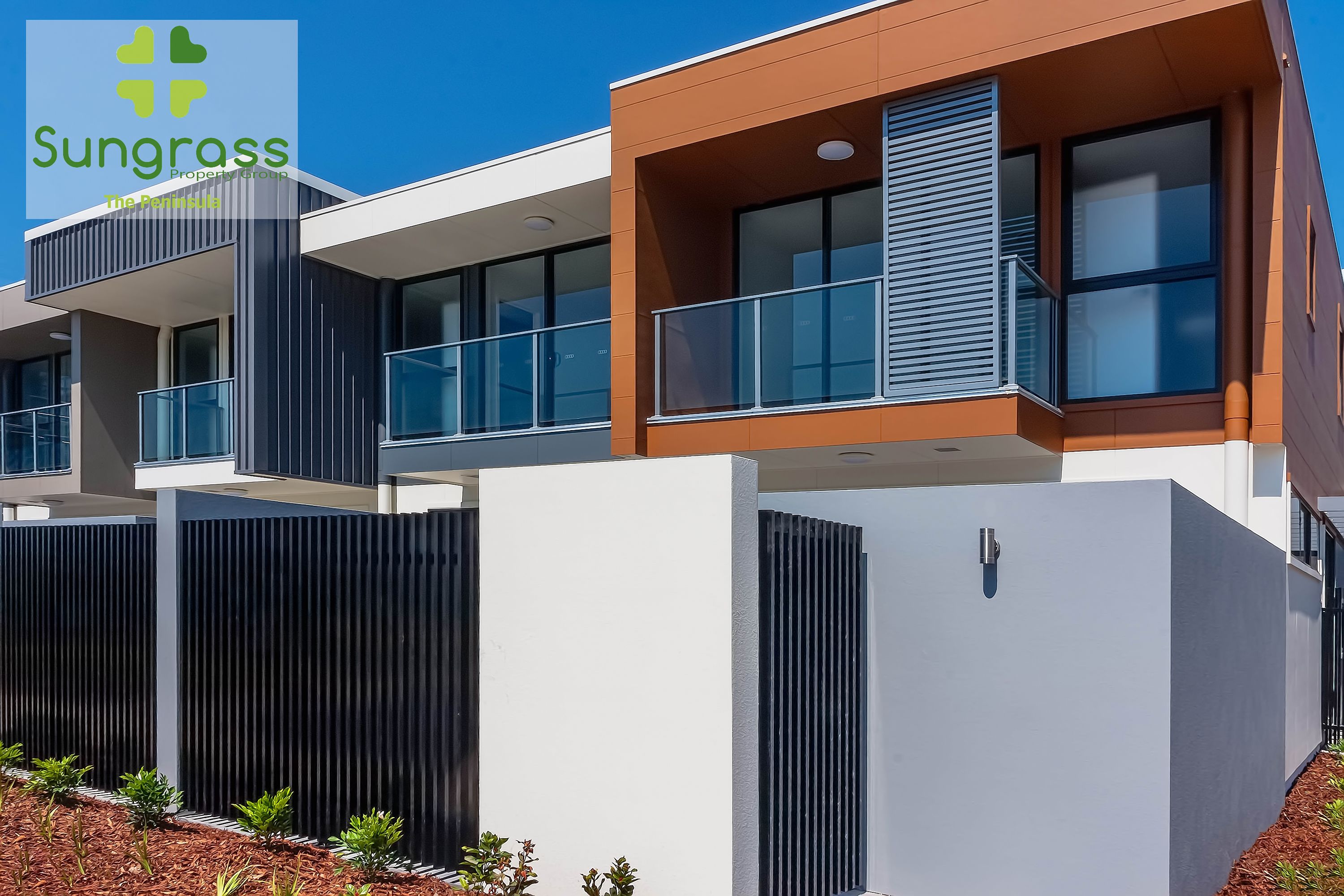 A modern multi-story residential building with balconies, large windows, and a flat roof.