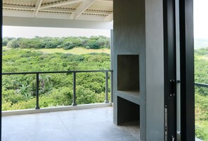 A balcony with a view of a lush green landscape.