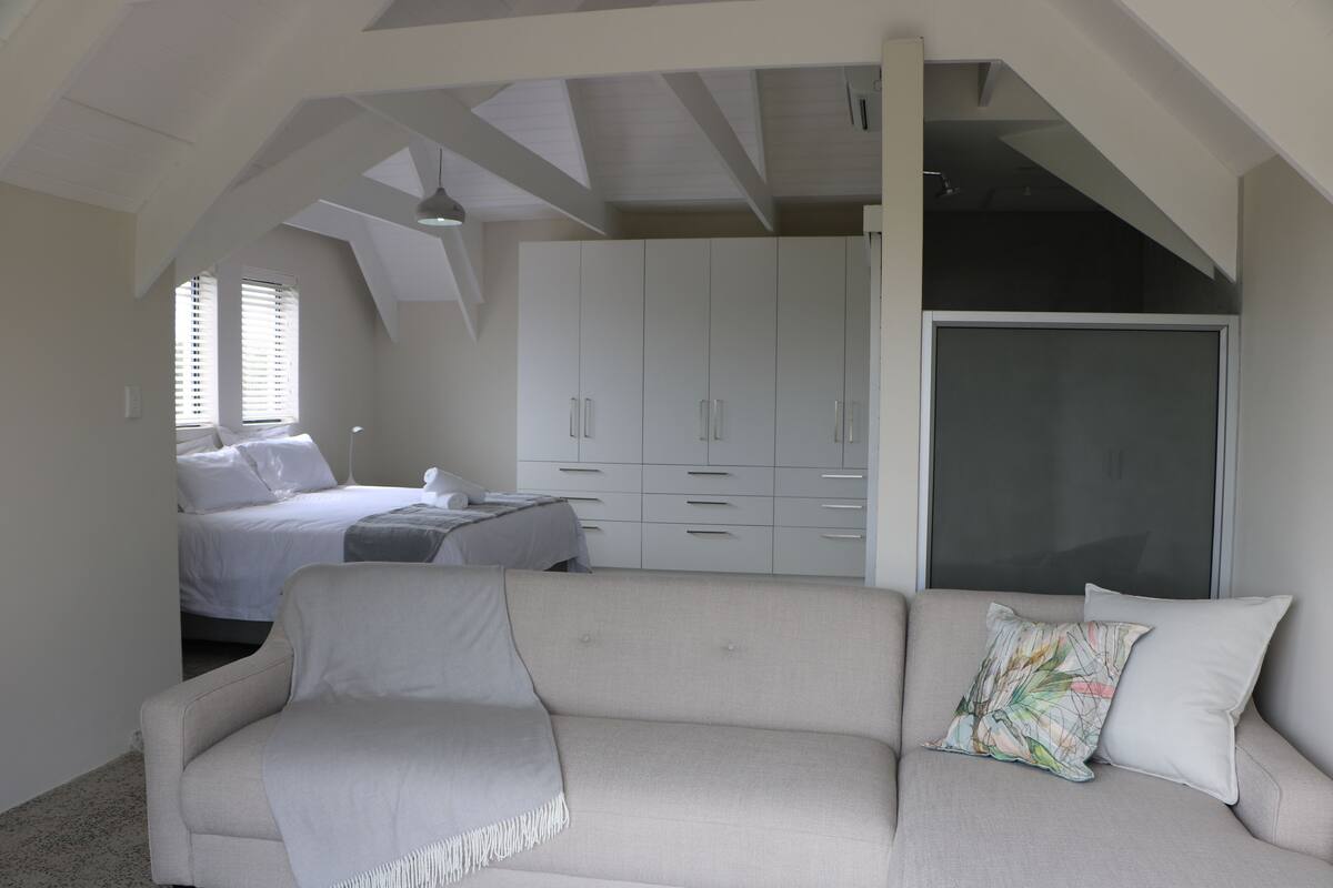 Une chambre à coucher avec un lit, un canapé, une armoire et une fenêtre.