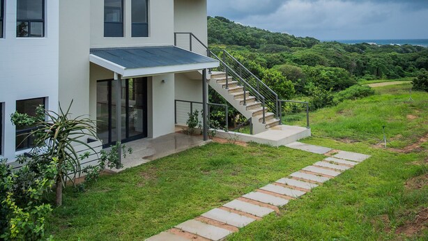 A modern two-story house with a covered porch and a staircase leading to the upper floor. - Apartments on The Eighteenth (KwaDukuza)