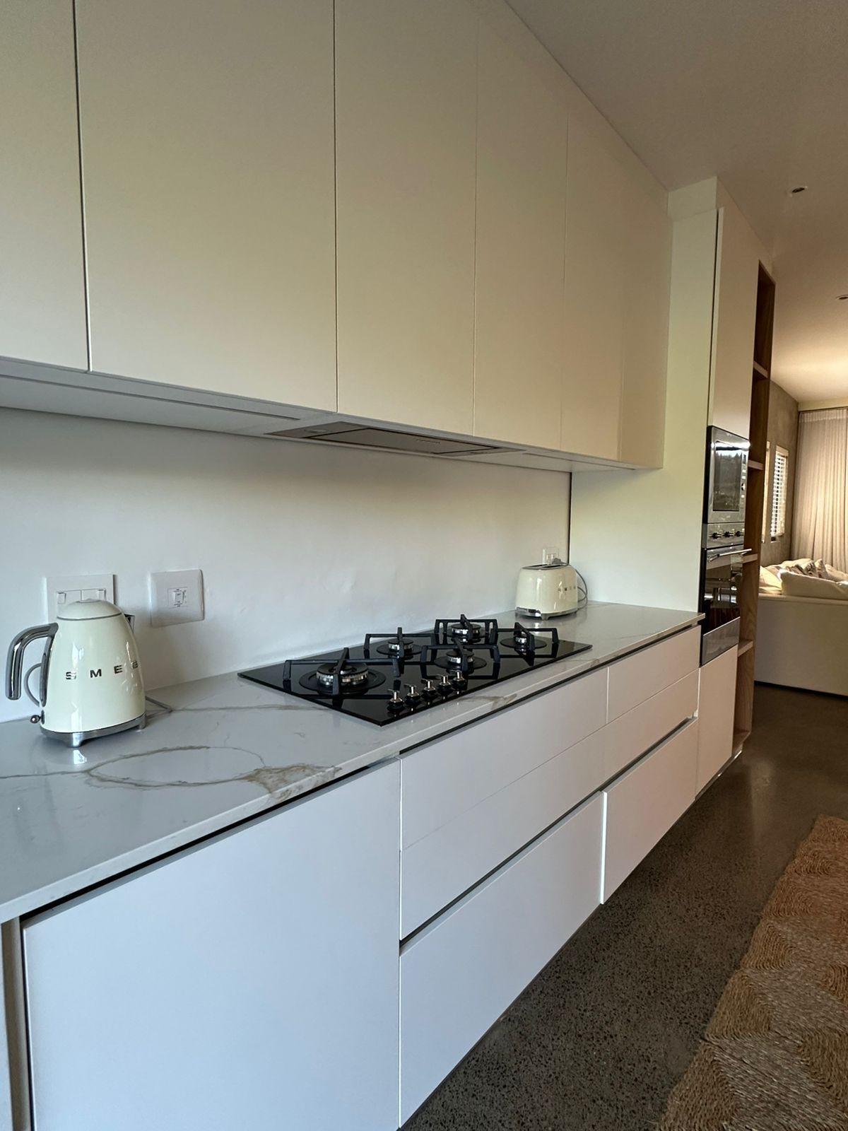 A modern kitchen with white cabinetry, a gas stove, and a kettle.