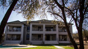 A two-story modern building with a swimming pool, surrounded by trees. - Tinyiko Kruger Lodge (Nkomazi)