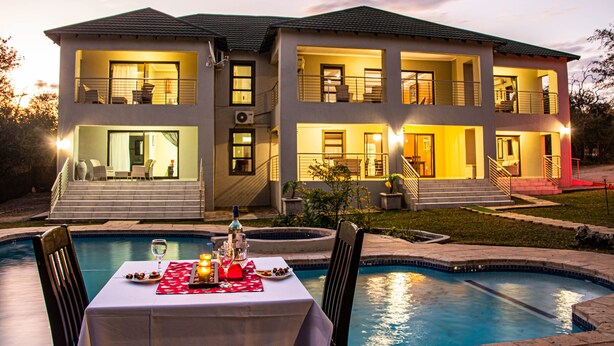A two-story house with a swimming pool, outdoor seating, and a well-lit balcony. - Tinyiko Kruger Lodge (Nkomazi)