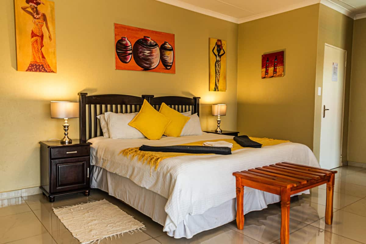Quarto bem arrumado com cama, mesas de cabeceira, um banco de madeira e obras de arte nas paredes.