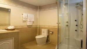 A bathroom with a toilet, a glass-enclosed shower, and a towel rack.