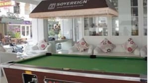 A billiards table with a pool cue rack, a sofa with cushions, and a sign for Sovereign.