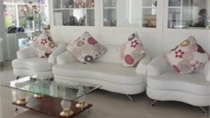 A modern living room with a white sofa set, glass coffee table, and decorative pillows.