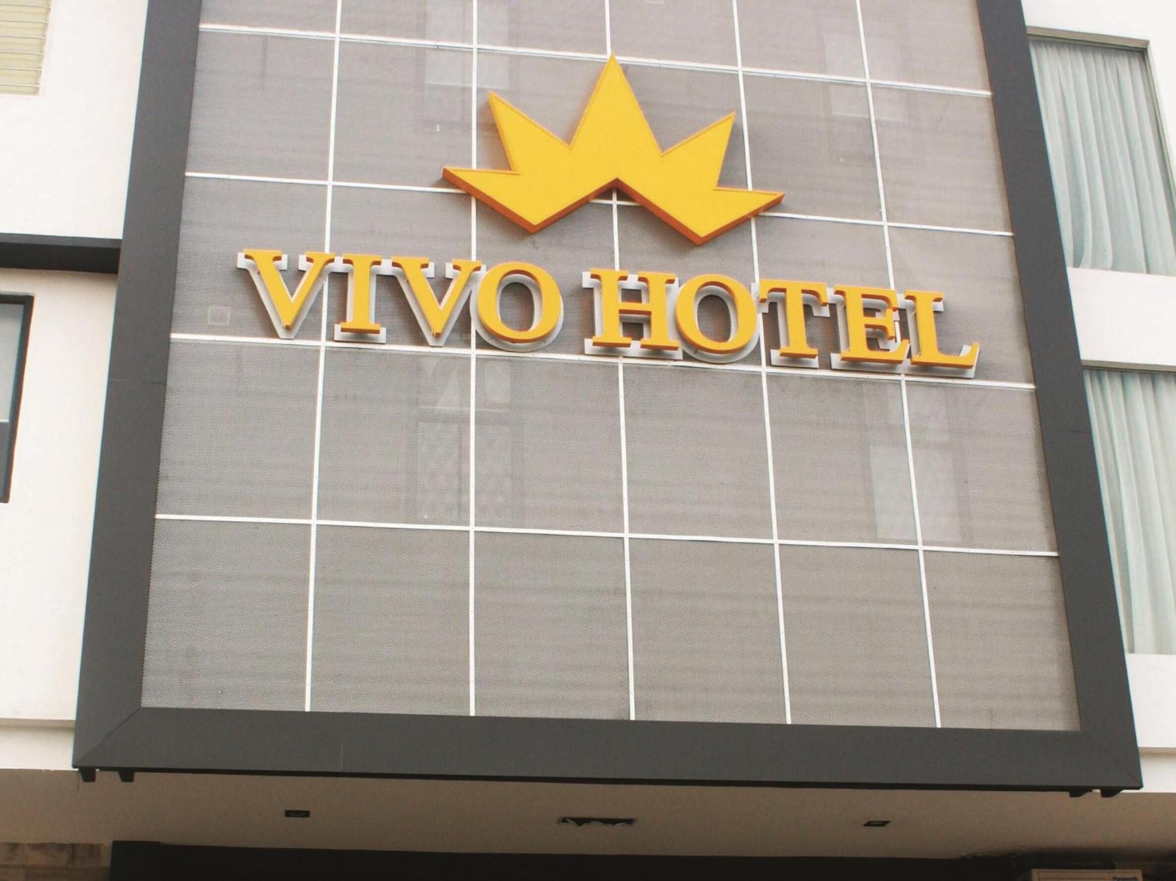 A hotel sign with the name "VIVO HOTEL" and a stylized crown symbol above the text.