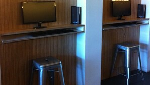 Una habitación con dos paredes de paneles de madera, un televisor de pantalla plana en cada una y un taburete metálico frente a cada televisor.
