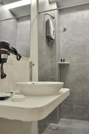 A modern bathroom with a white sink, a handheld showerhead, and a towel rack. - Vivo Hotel (Kuantan)