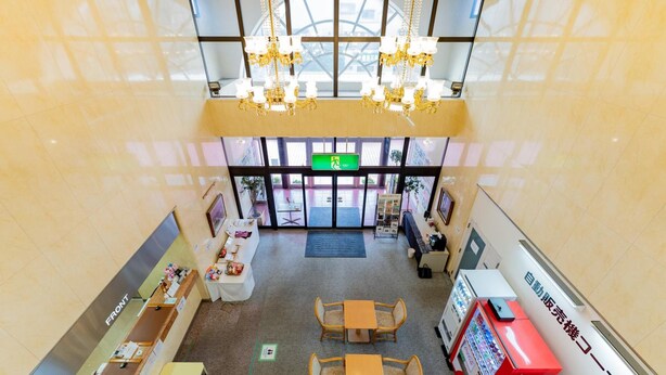 A spacious lobby with a reception desk, seating area, vending machines, and a large glass entrance.