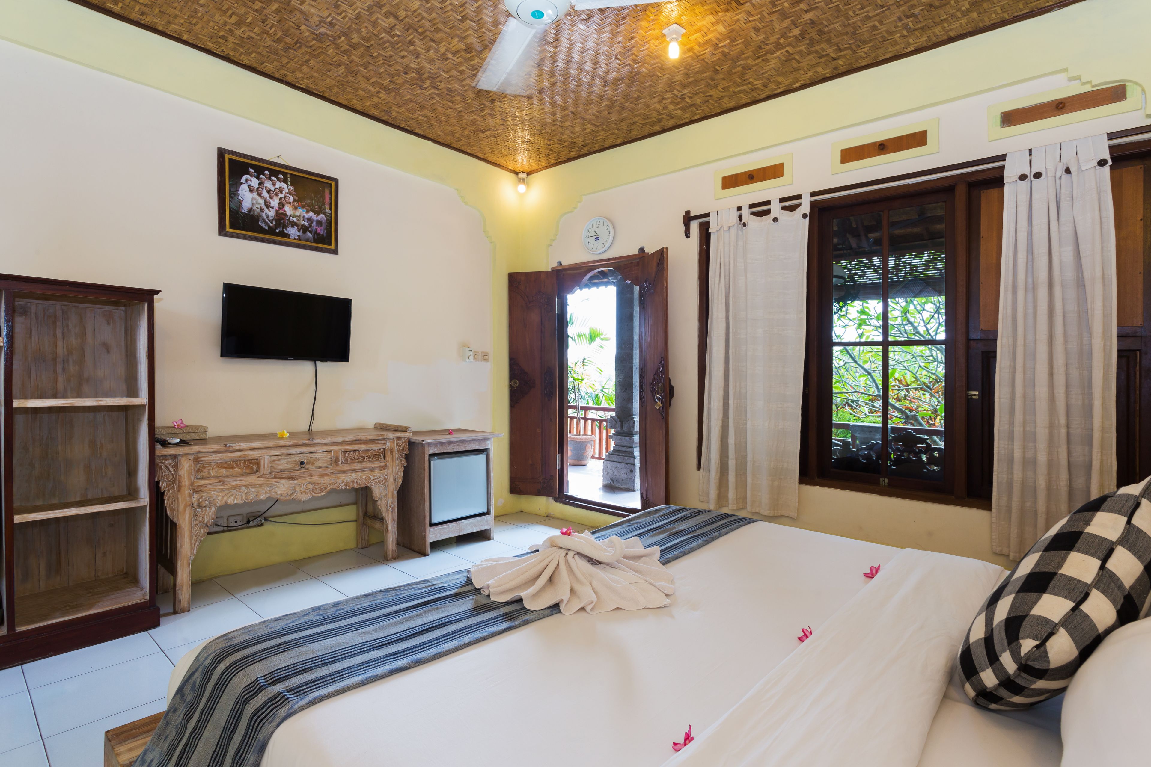 A bedroom with a bed, a desk, a television, and a window with curtains.