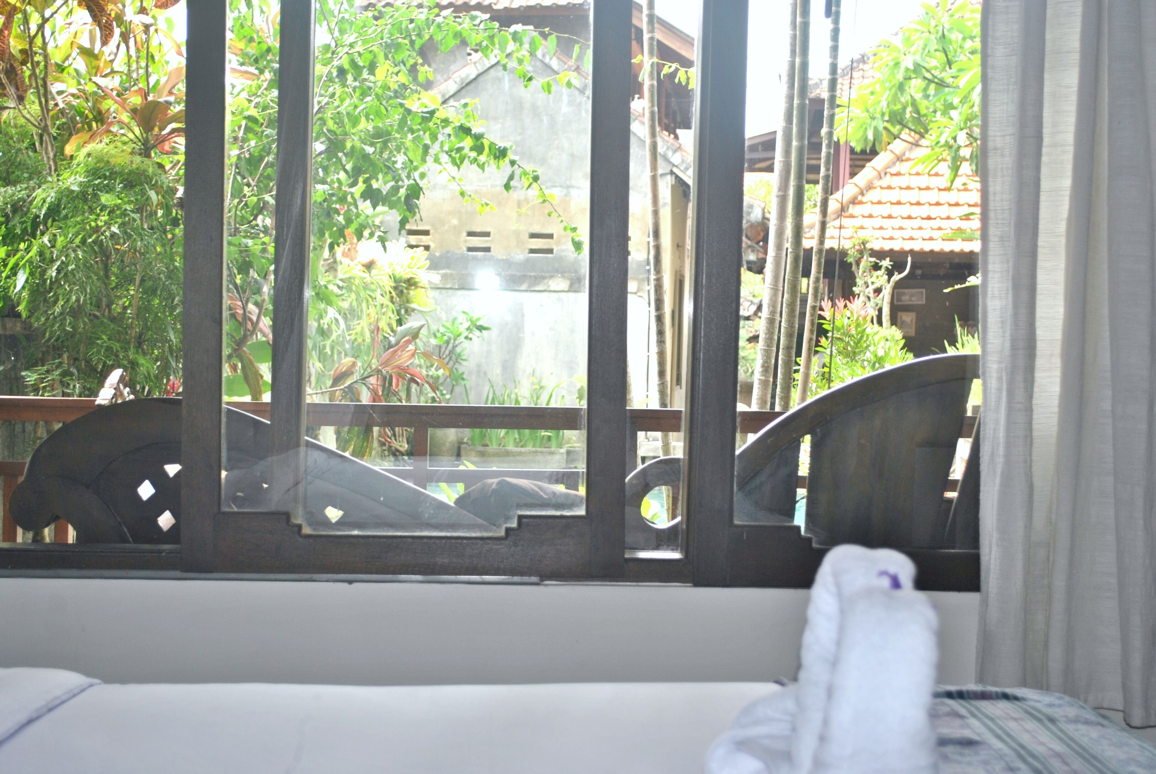 A room with a window overlooking a garden and a building.