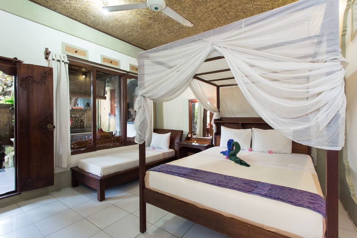 A room with a bed, a window, a door, and a ceiling fan.