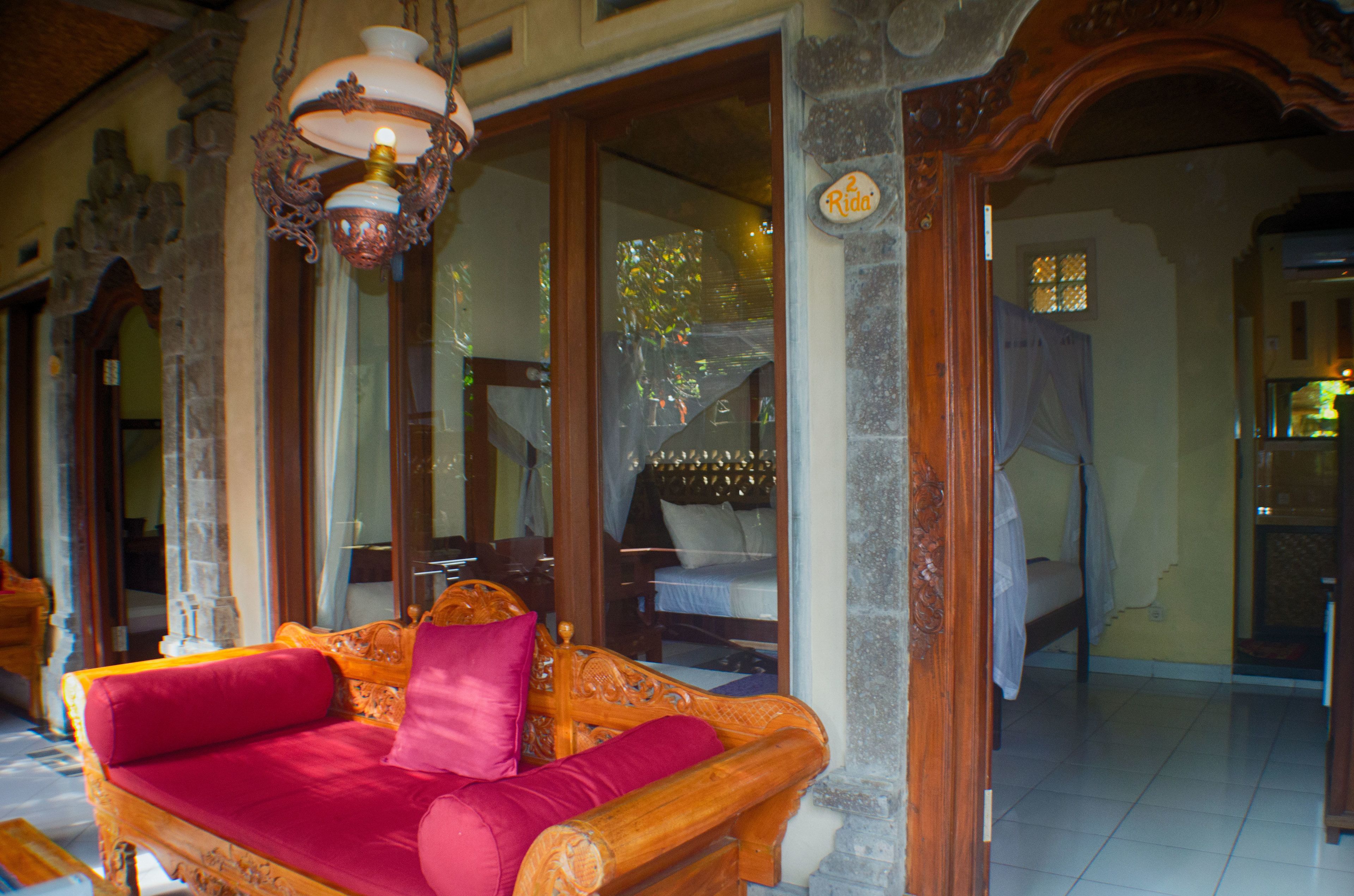 Una habitación tradicional con sofá de madera, cama y candelabro.