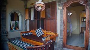 A traditional room with a wooden bench, a large mirror, and stone walls. - Rumah Roda (Ubud)